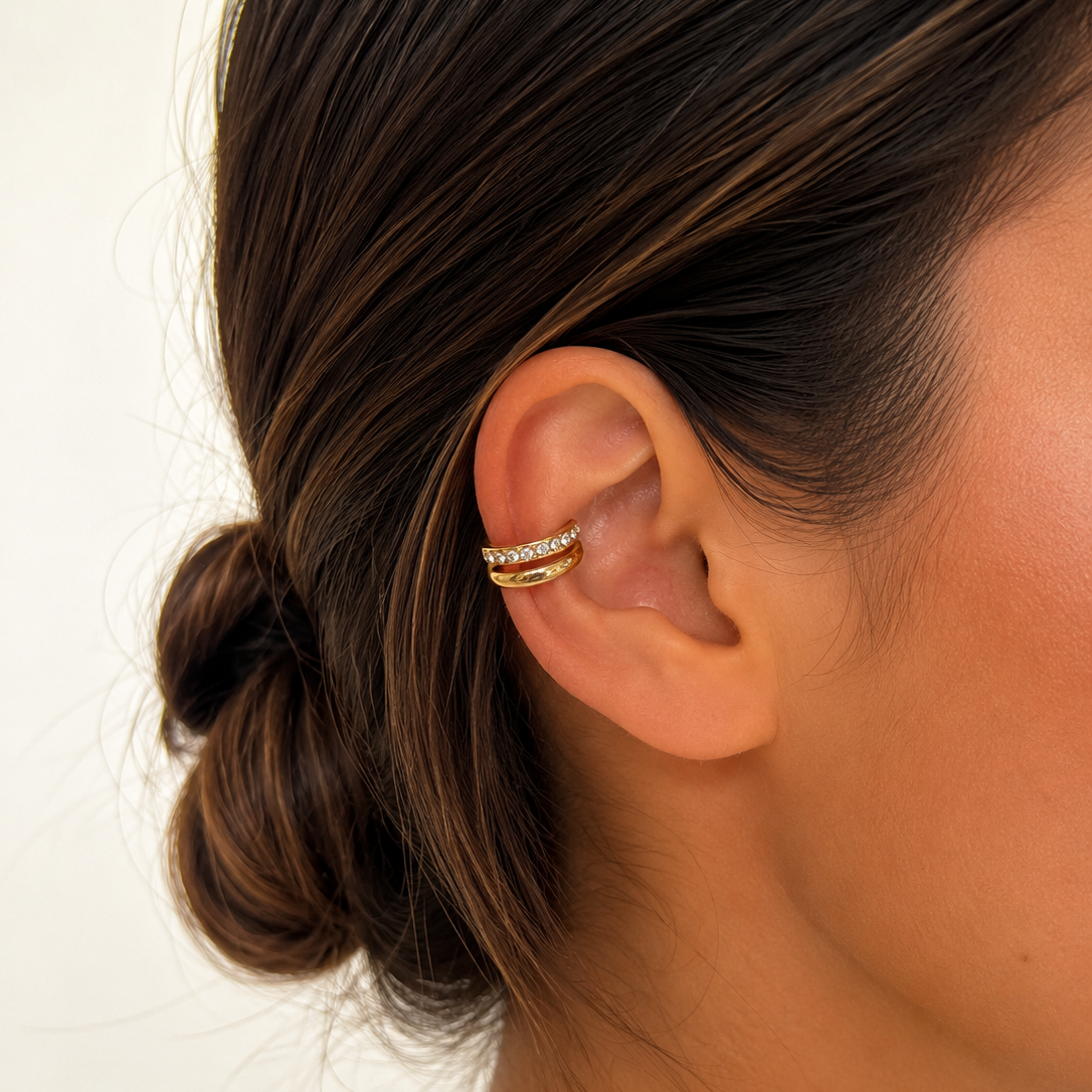 Ear cuff doré serti de pierres de zirconium porté sur l'oreille