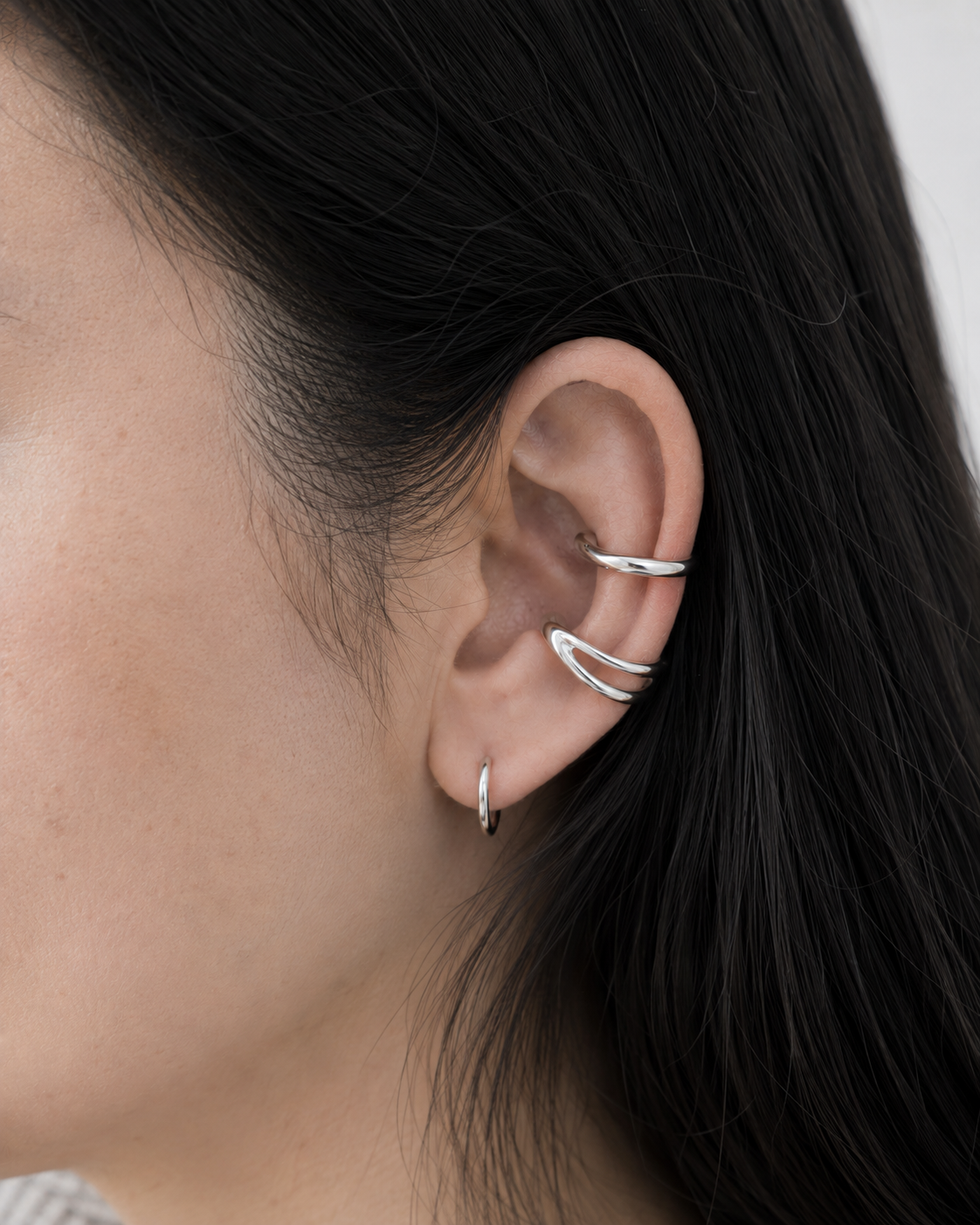 Ear cuff porté au milieu du cartilage avec une petite créole sur une oreille féminine