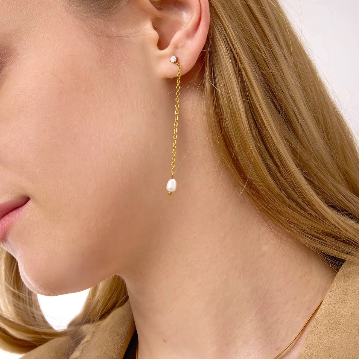 Boucles d’oreilles pendantes dorées avec chaîne fine et perle blanche. Un modèle minimaliste et élégant, idéal au quotidien comme en soirée. Hypoallergénique