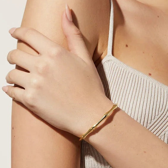 Bracelet bambou doré porté seul au poignet d'une femme