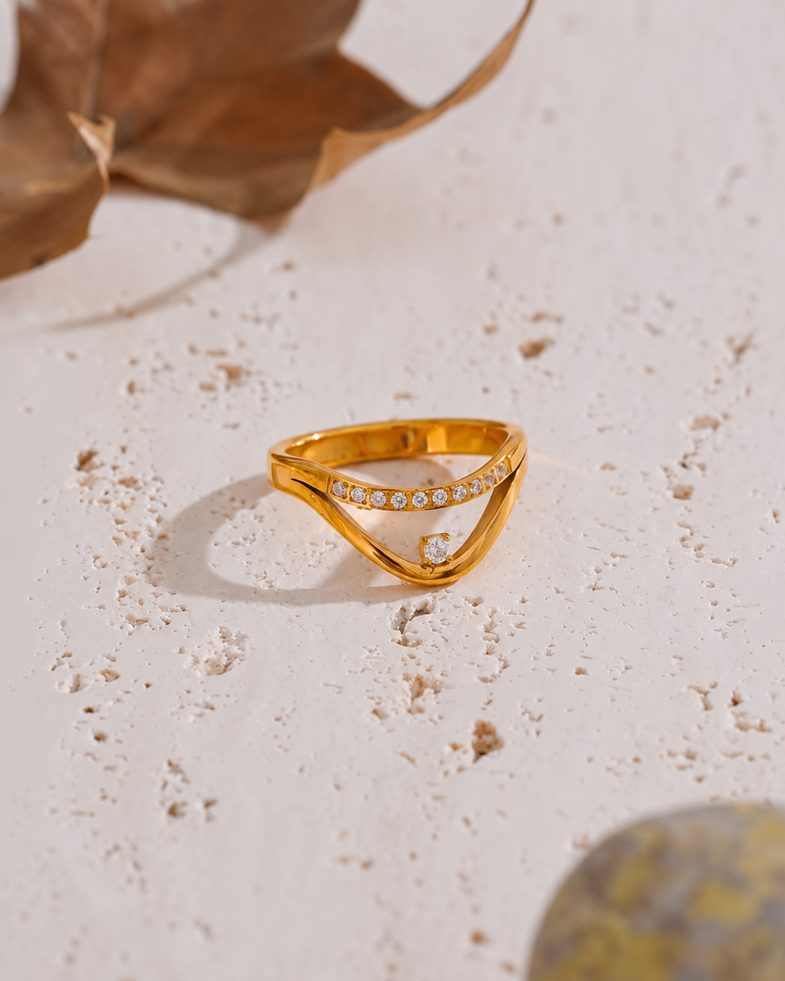 Bague Élyra en acier chirurgical doré avec zircons, bijou élégant photographié dans un décor raffiné
