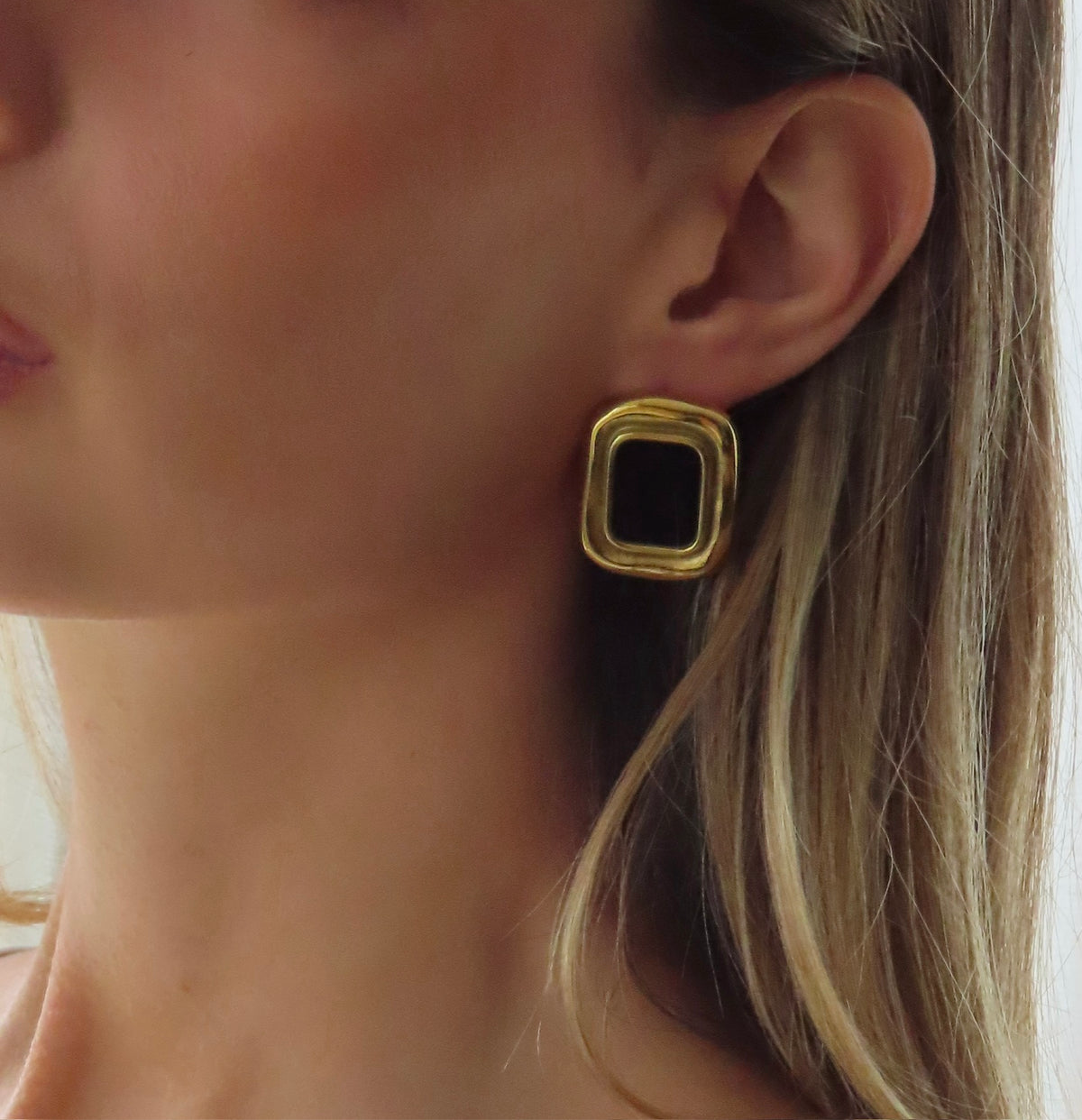 Boucle d'oreille Marylou dorée à pierre noire portée, cheveux longs blonds