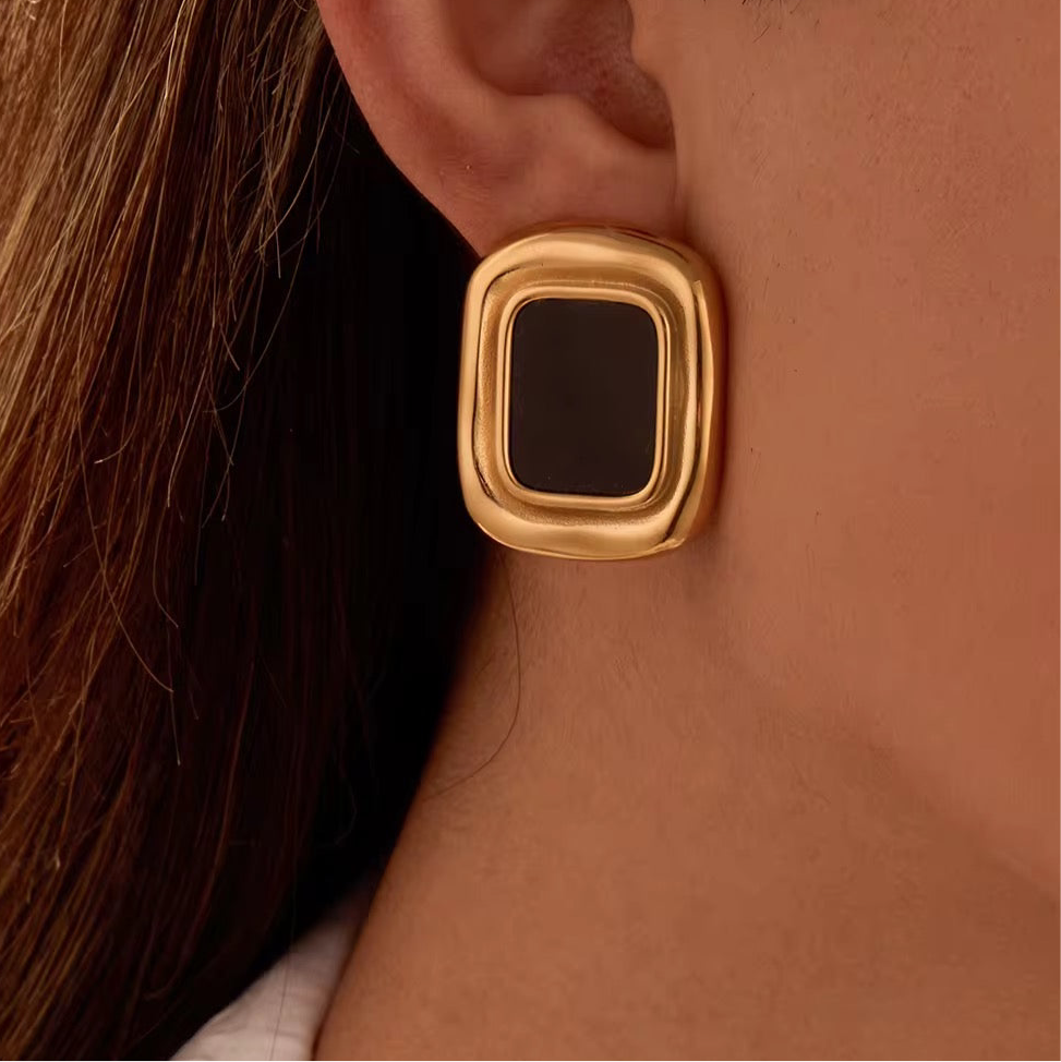 Gros plan d'une boucle d'oreille vintage Marylou portée, cadre doré et pierre noire