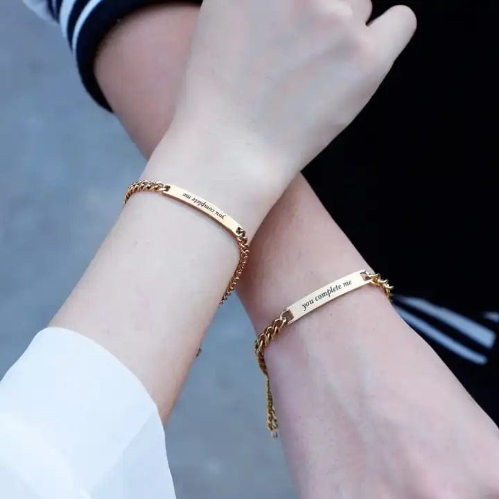 Bracelet couple personnalisé Le Duo : deux gourmettes dorées gravées portées aux poignets