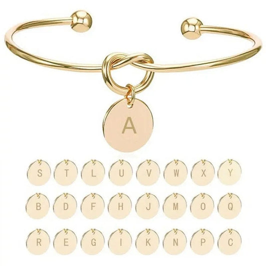 Bracelet jonc fin Initial doré, nœud et médaillon gravé de la lettre A, sur fond blanc