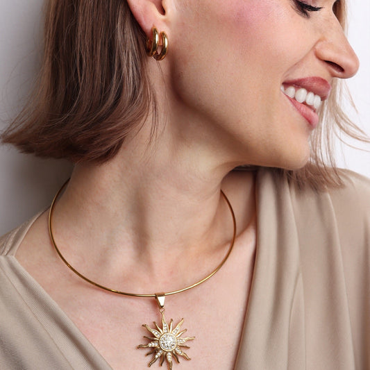 Femme portant un choker doré rigide avec pendentif soleil XL serti de strass