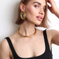 Choker ras de cou Dalia doré porté avec un débardeur noir et de grosses boucles d'oreilles