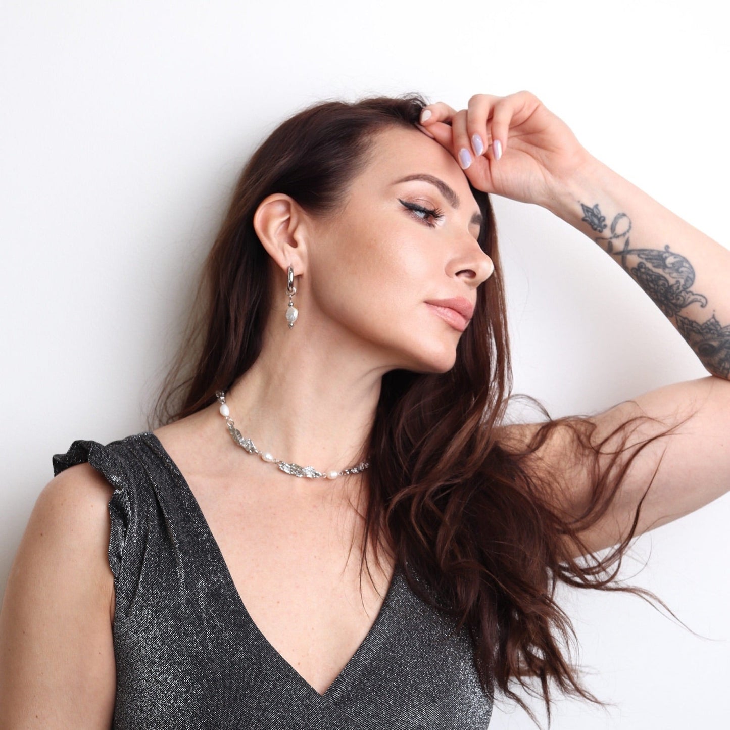 Collier argenté avec perles porté par une femme au style rock chic avec top brillant noir