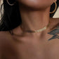 Collier chaîne plate doré Ashley porté à la base du cou avec des créoles