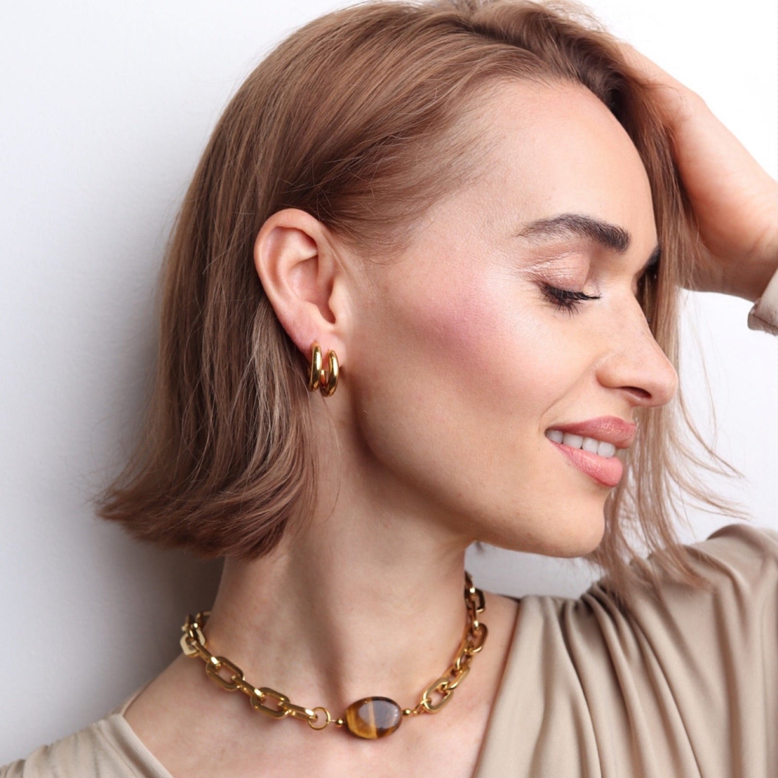 Collier choker doré avec pierre œil de tigre porté par une femme au look raffiné et lumineux
