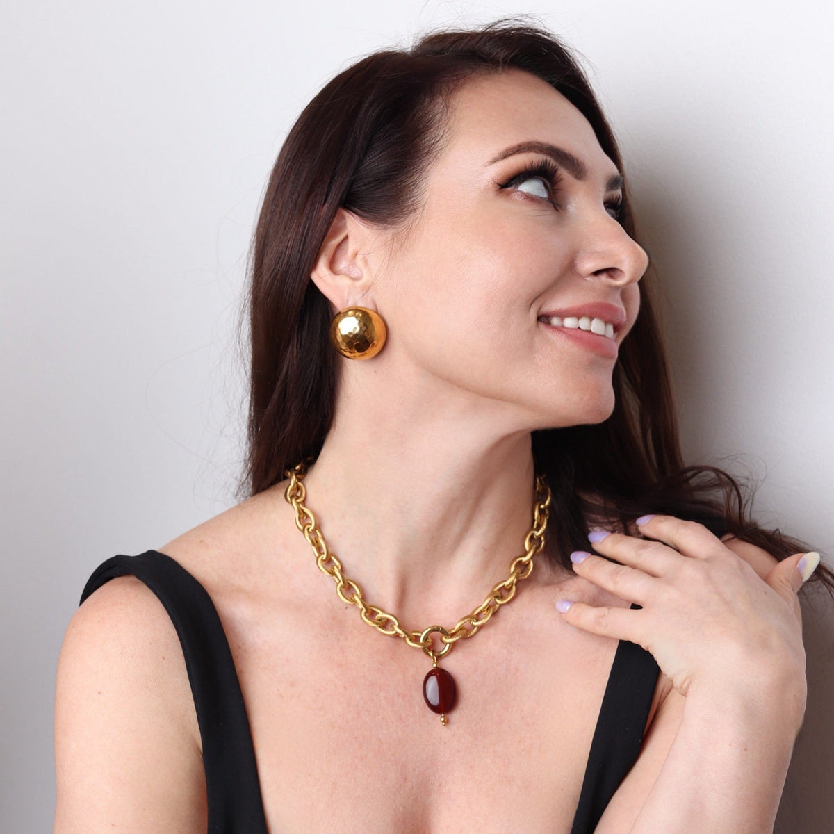 Femme élégante portant un collier doré chic avec pierre rouge naturelle