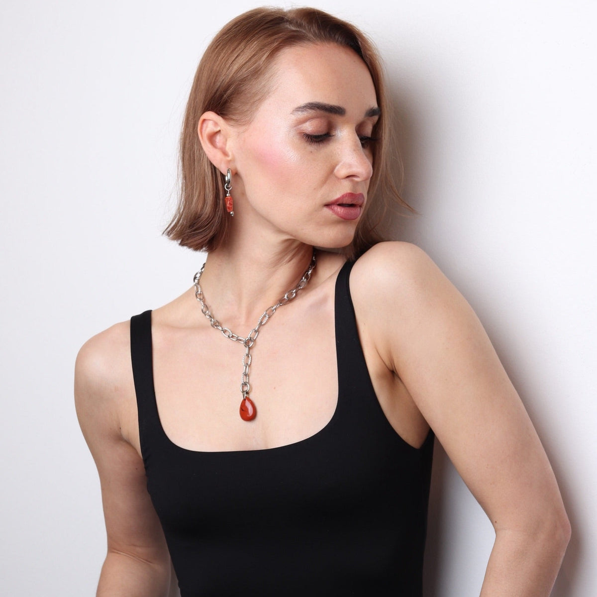 Femme portant un collier argenté avec pendentif pierre rouge naturelle