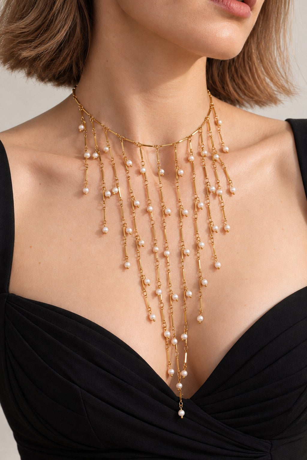 Collier plastron Séraphine doré porté en choker, franges de perles naturelles sur un décolleté noir