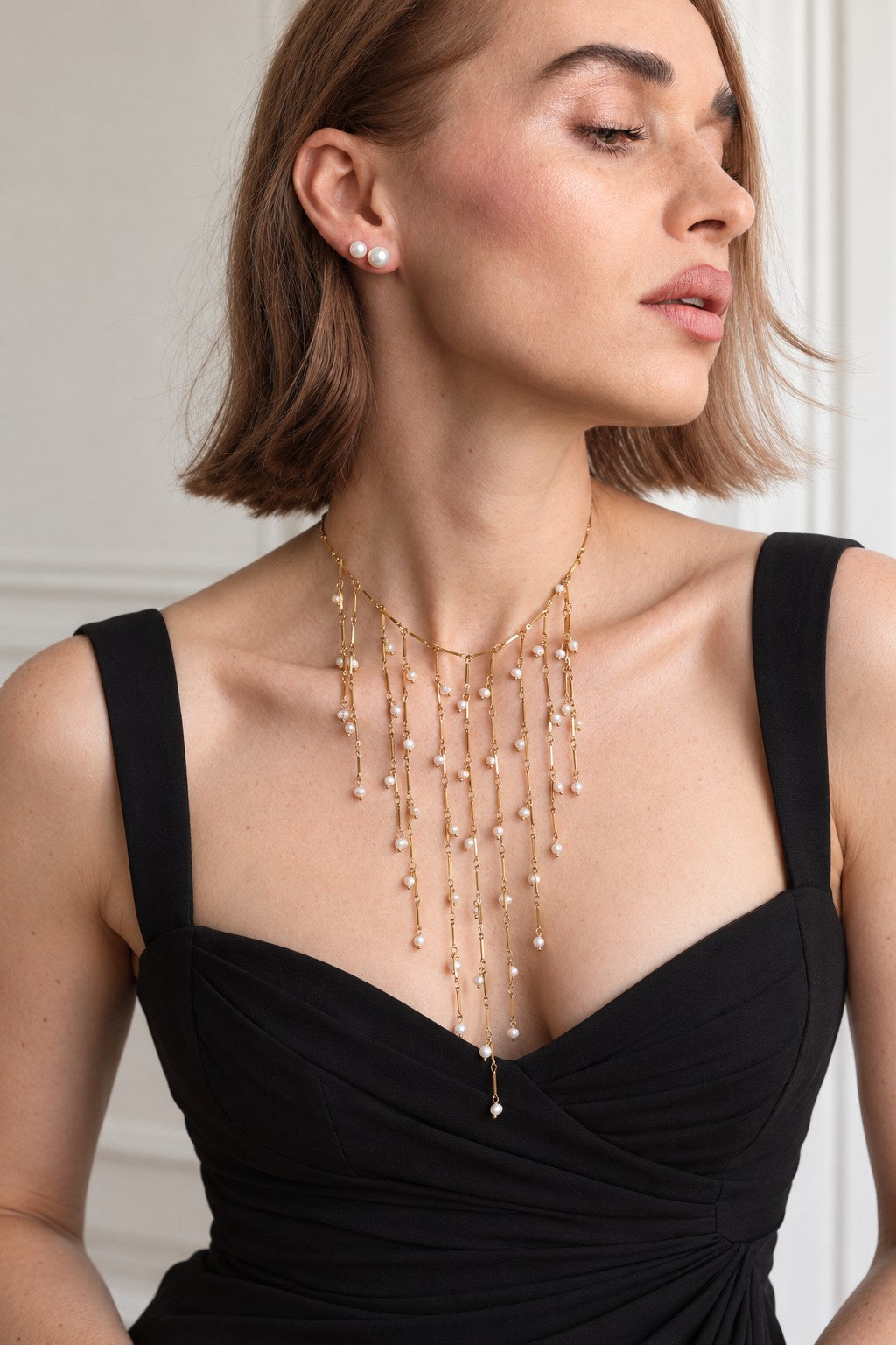 Collier plastron perles naturelles Séraphine doré porté avec une robe noire et des puces perle