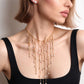 Collier plastron Séraphine doré porté sur un top noir à encolure carrée, franges de perles