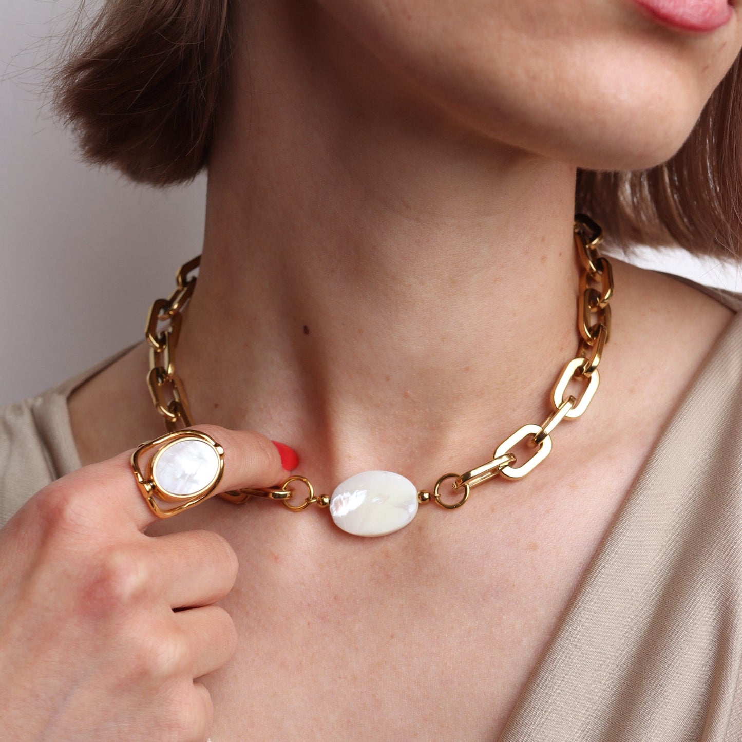 Collier grosse maille doré avec pierre blanche nacrée porté avec une bague assortie élégante