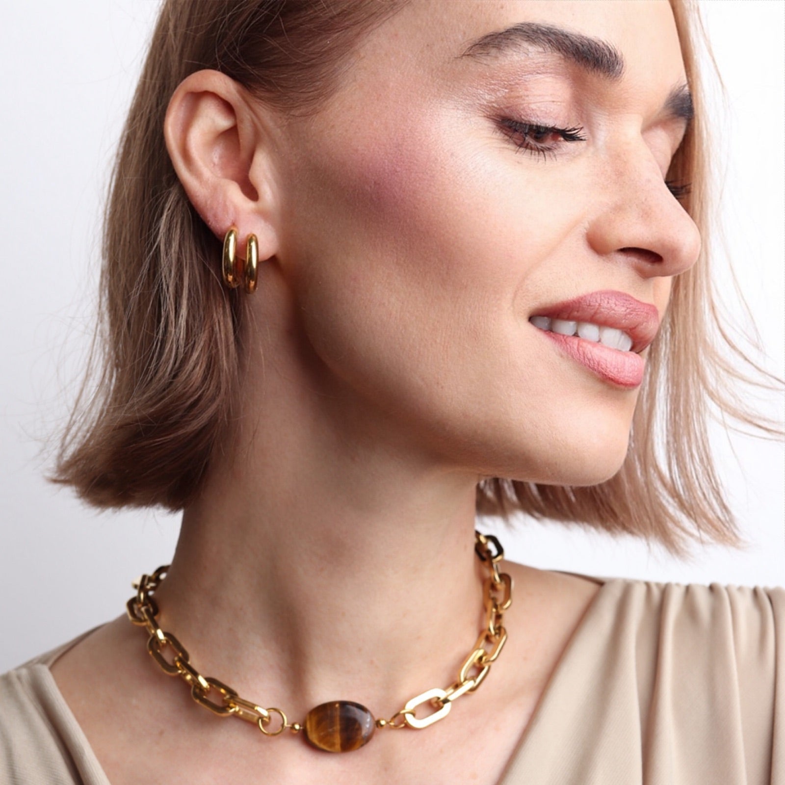 Collier doré à grosse maille avec pierre œil de tigre porté avec une bague assortie élégante